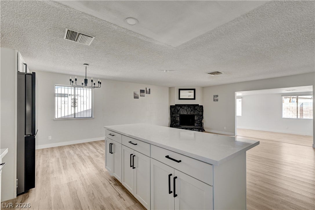4442 Eureka Circle, Las Vegas, NV 89103 An open floorplan connects the central kitchen island directly to a cozy fireplace area.