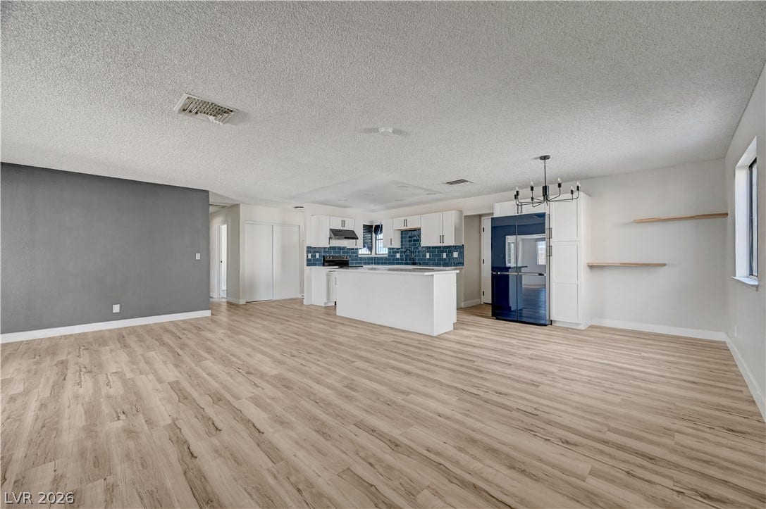 4442 Eureka Circle, Las Vegas, NV 89103 An open layout connects a spacious living area to the kitchen featuring modern wood-style flooring.