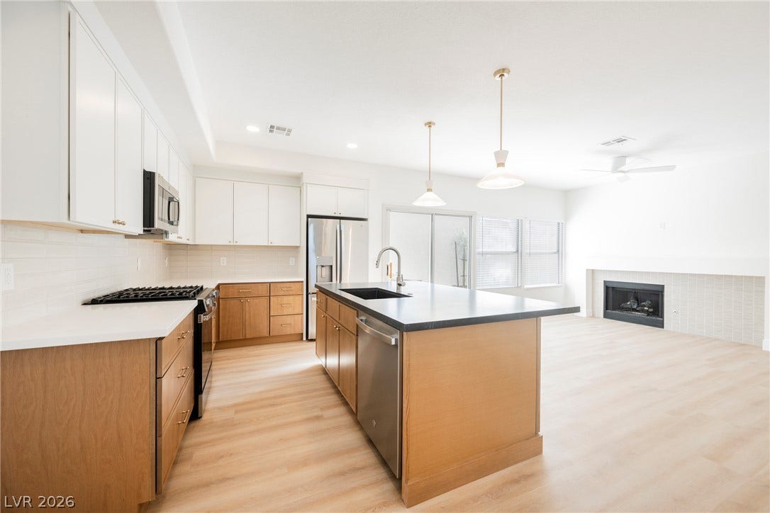 Gleaming wood floors connect the modern kitchen directly to a cozy fireplace-warmed living area.