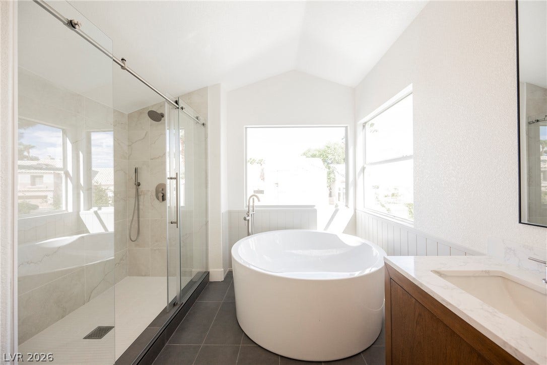 Vaulted ceilings and dark tile floors frame a contemporary freestanding tub and glass shower.