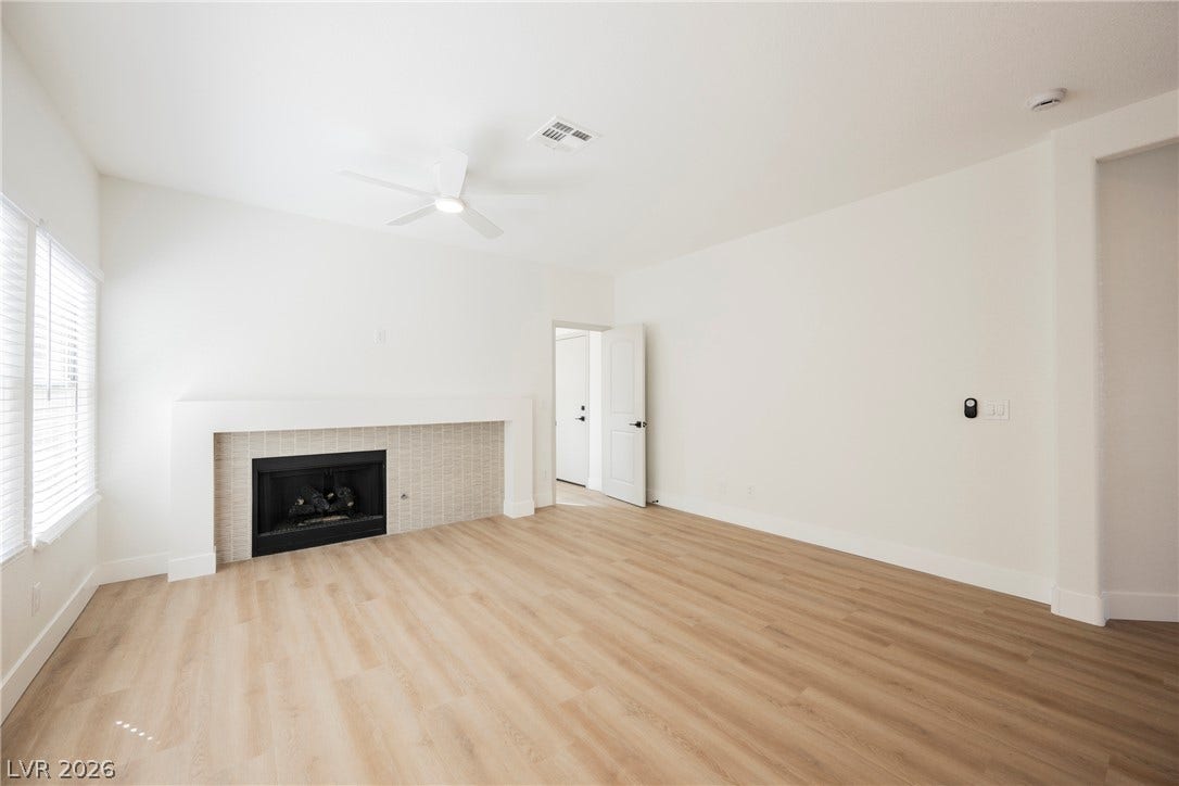 Smooth wood-style flooring and a tiled fireplace ground this light-filled room.