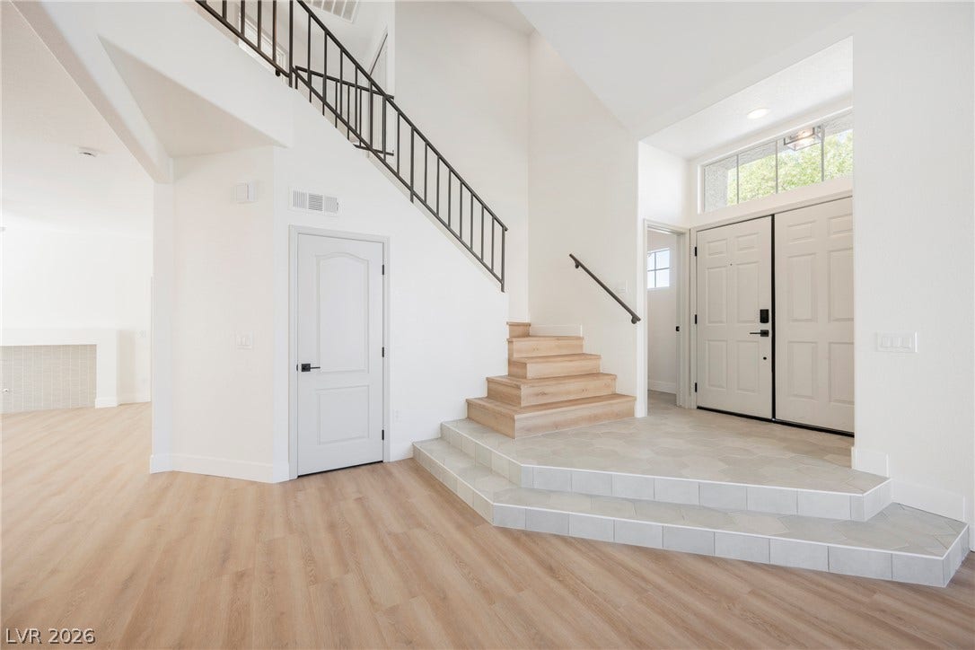 Clean lines and light-toned flooring define this open, multi-level entryway with a modern staircase.