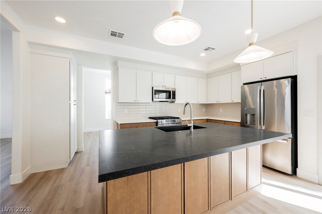 Rich wood floors complement clean cabinetry and a contrast-toned center island in this kitchen.