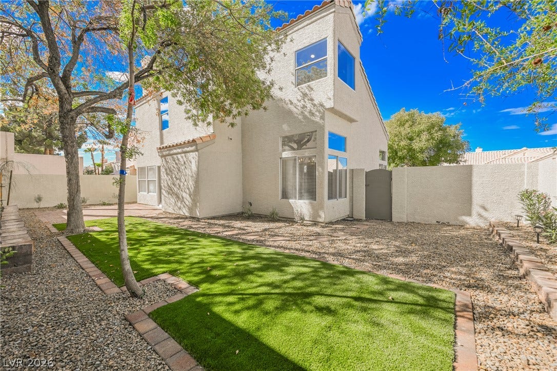 Lush green turf contrasts beautifully with clean gravel landscaping in this private backyard oasis.
