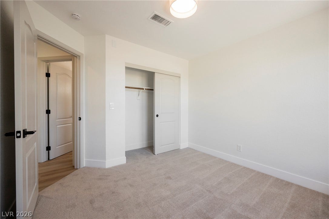 Soft carpeting pairs with neutral walls in this comfortable secondary bedroom.