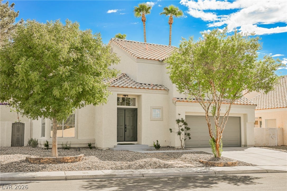 Spanish tile roofing and mature desert landscaping create an appealing exterior facade.