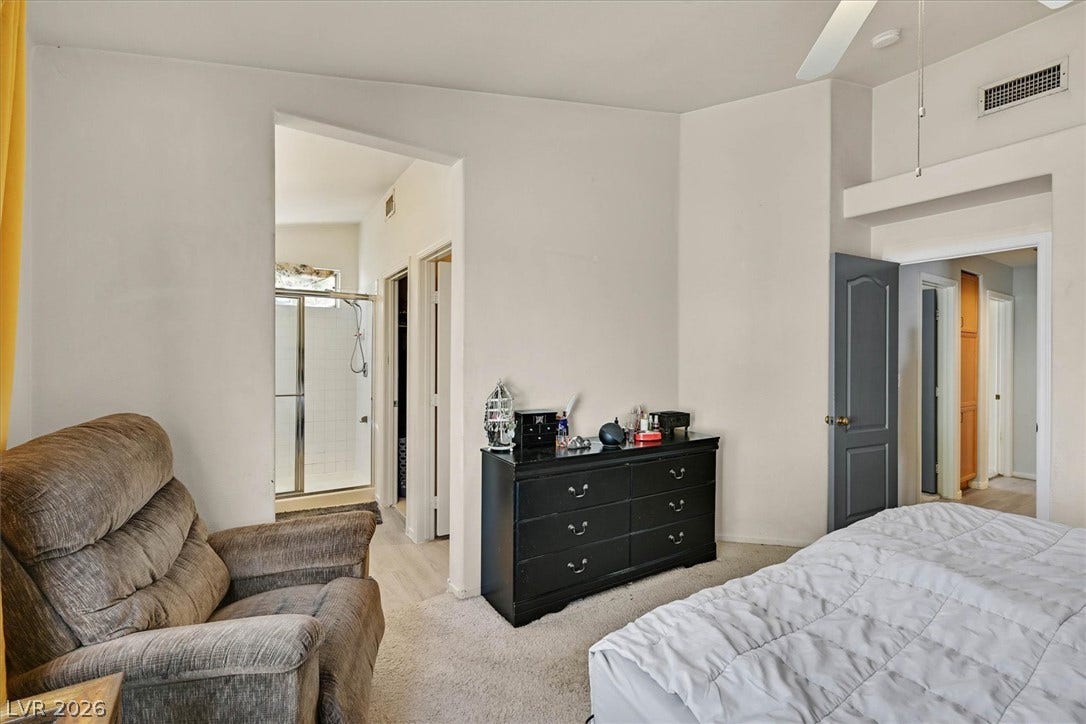 8830 Haviland Road, Las Vegas, NV 89123 An open doorway connects the carpeted bedroom with vaulted ceilings to an ensuite bathroom.