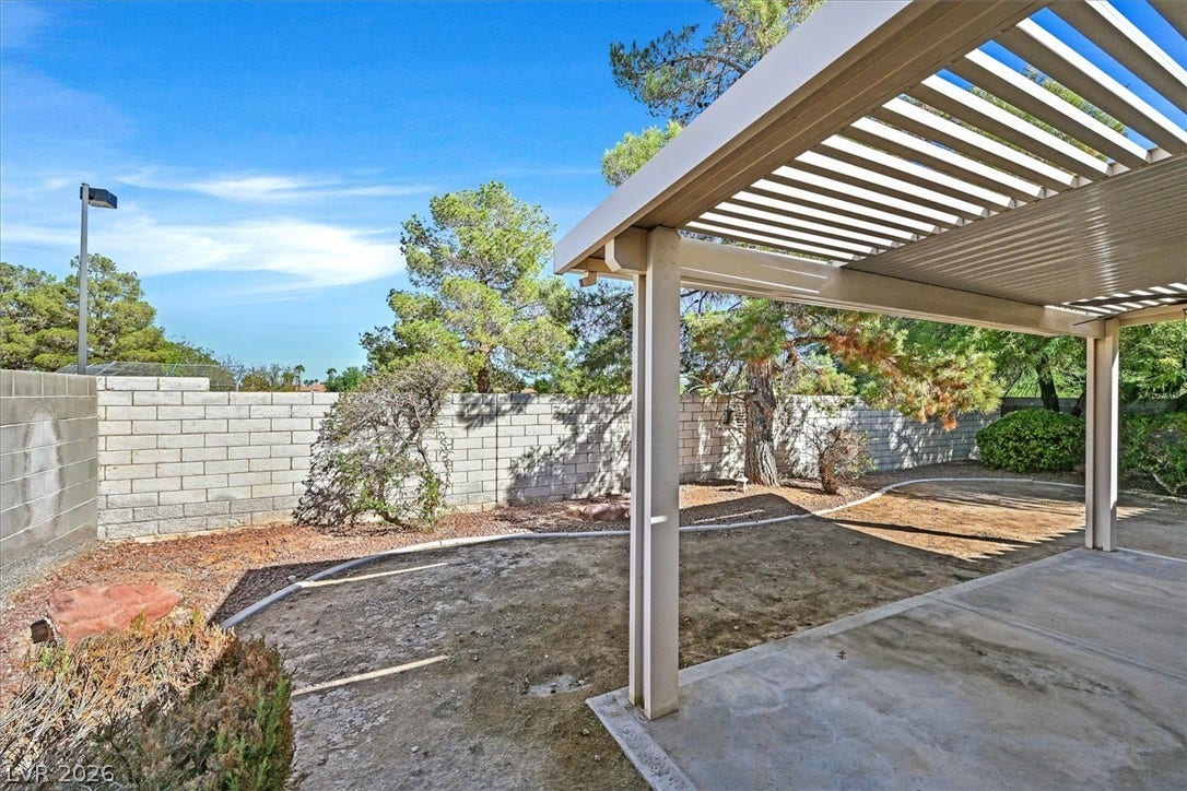8830 Haviland Road, Las Vegas, NV 89123 A covered concrete patio overlooks a fenced backyard lined with mature trees.
