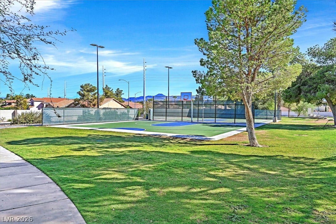 8830 Haviland Road, Las Vegas, NV 89123 An outdoor basketball court stands surrounded by manicured lawns and mature trees under clear skies.