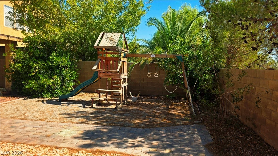 5087 Caprock Canyon Avenue, Las Vegas, NV 89139 Lush mature trees shade a private backyard complete with a brick-paved patio and playground setup.