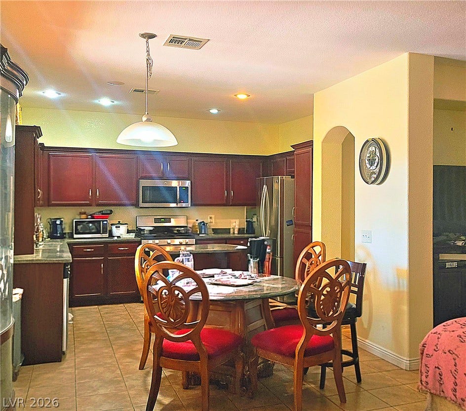5087 Caprock Canyon Avenue, Las Vegas, NV 89139 An arched doorway leads into this kitchen featuring rich wooden cabinetry and tile flooring.