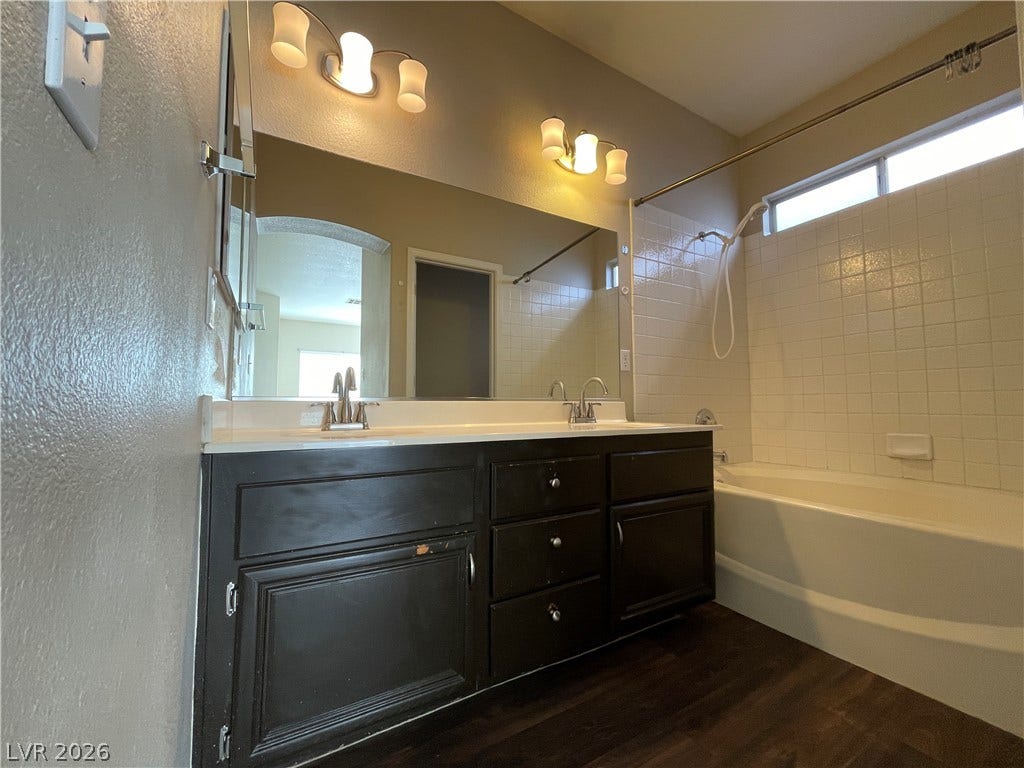 7873 Blue Brook Drive, Las Vegas, NV 89147 Dark wood flooring and a dual vanity with dark cabinetry anchor this well-appointed bathroom.