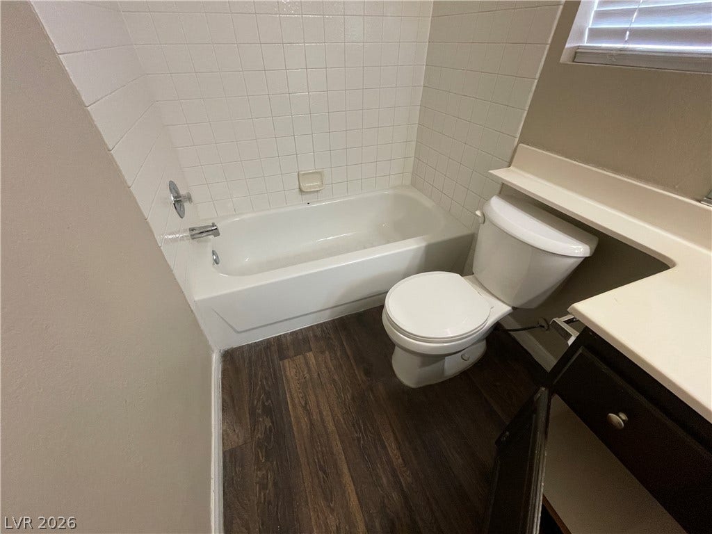 7873 Blue Brook Drive, Las Vegas, NV 89147 Warm wood-look flooring contrasts beautifully with classic white wall tiling in this functional bathroom.