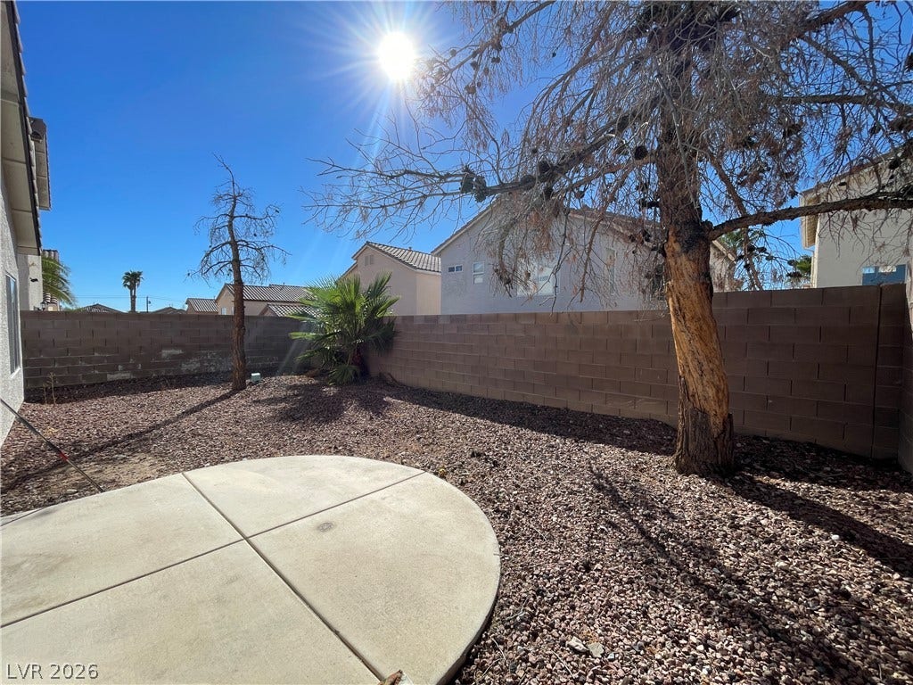 7873 Blue Brook Drive, Las Vegas, NV 89147 An enclosed outdoor area features low-maintenance gravel landscaping and a concrete patio pad under sunny skies.