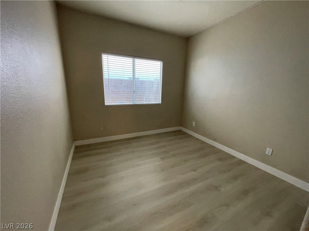 7873 Blue Brook Drive, Las Vegas, NV 89147 Smooth wood-look flooring and a wide window define this versatile bedroom space.