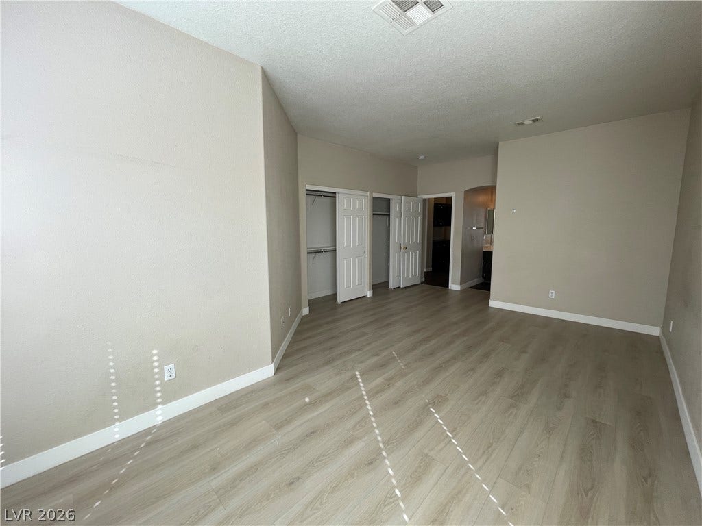 7873 Blue Brook Drive, Las Vegas, NV 89147 Smooth wood-style flooring runs throughout this bedroom featuring dual built-in closets.