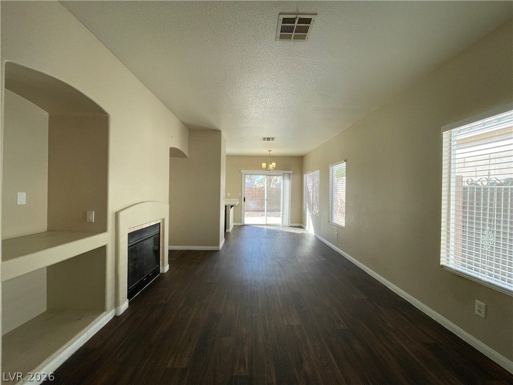 7873 Blue Brook Drive, Las Vegas, NV 89147 Rich wood-look flooring and a cozy fireplace anchor this inviting open-concept living area.