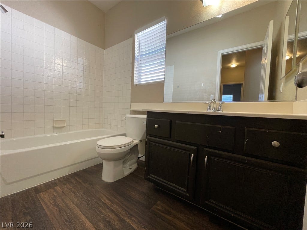 7873 Blue Brook Drive, Las Vegas, NV 89147 Rich wood-look flooring and a tiled tub surround anchor this classic bathroom space.