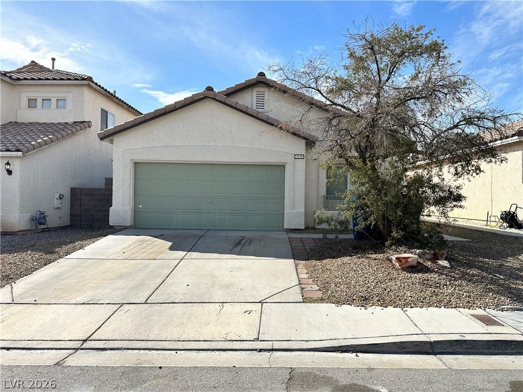 7873 Blue Brook Drive, Las Vegas, NV 89147 A classic stucco exterior features a tile roof and a concrete driveway leading to the garage.