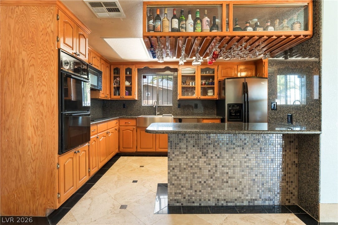 Rich wood cabinetry meets stone countertops and tile accents in this functional kitchen space.