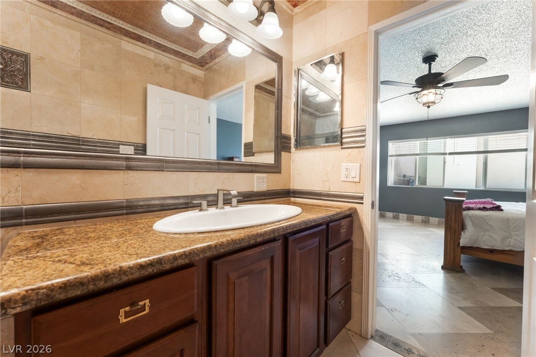 Richly veined stone countertops and warm wood cabinetry anchor this elegant primary washroom.