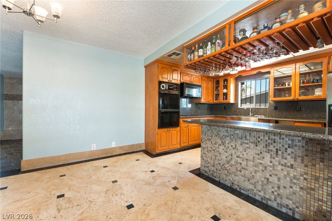 Gleaming tile floors and custom cabinetry anchor this functional culinary space with elevated bar seating.