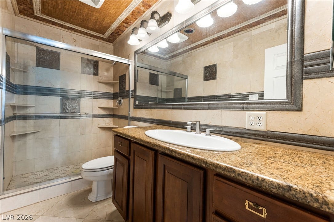 Ornate tilework, granite countertops, and a glass-enclosed shower define this classic bathroom space.