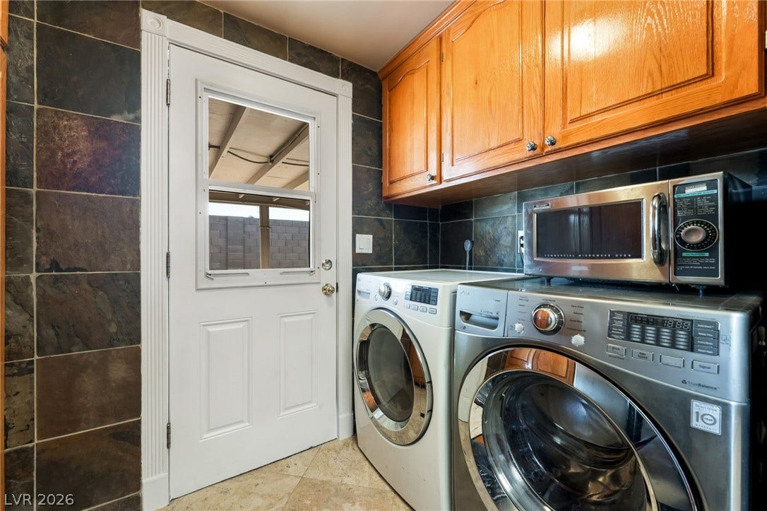 A functional utility space includes built-in cabinetry, natural stone wall tiles, and exterior door access.