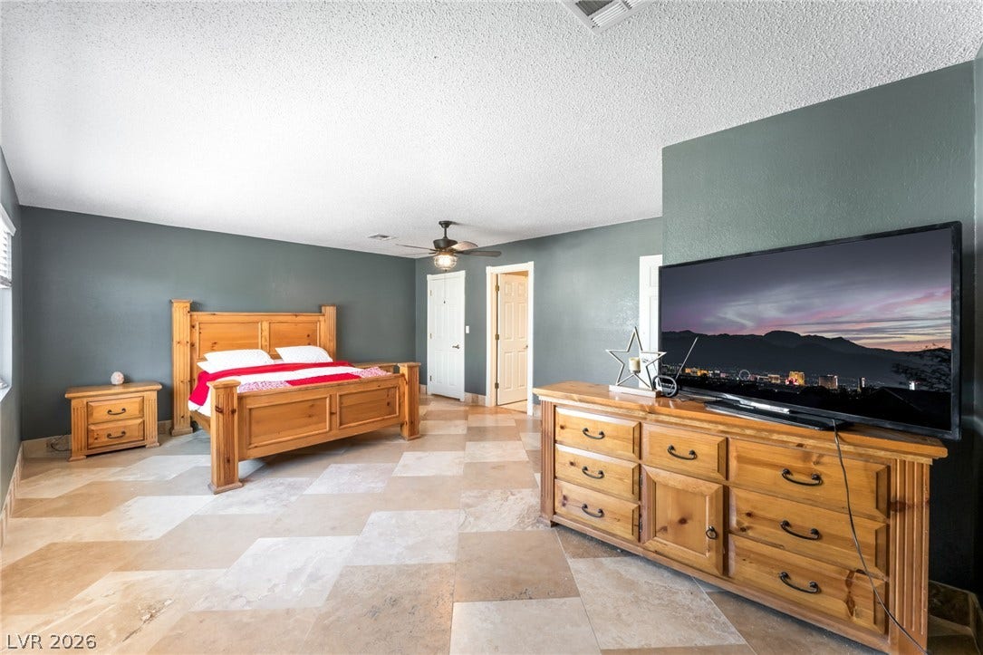 A spacious bedroom displays large-format tile flooring and private access to adjacent rooms.