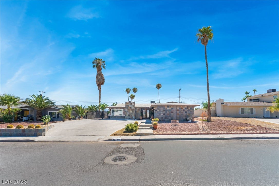 A wide concrete driveway leads to this midcentury desert home accented with stone veneer.
