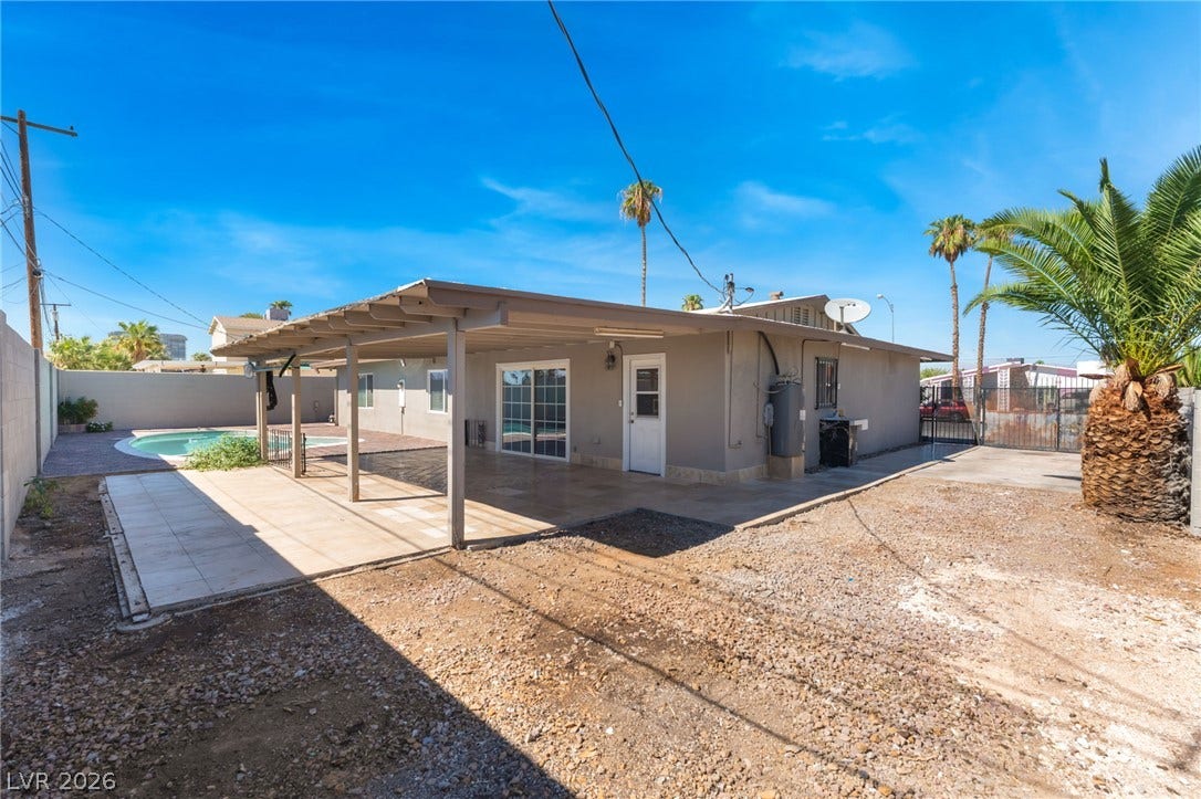 An expansive covered patio provides comfortable outdoor shelter beside the sunny backyard pool area.