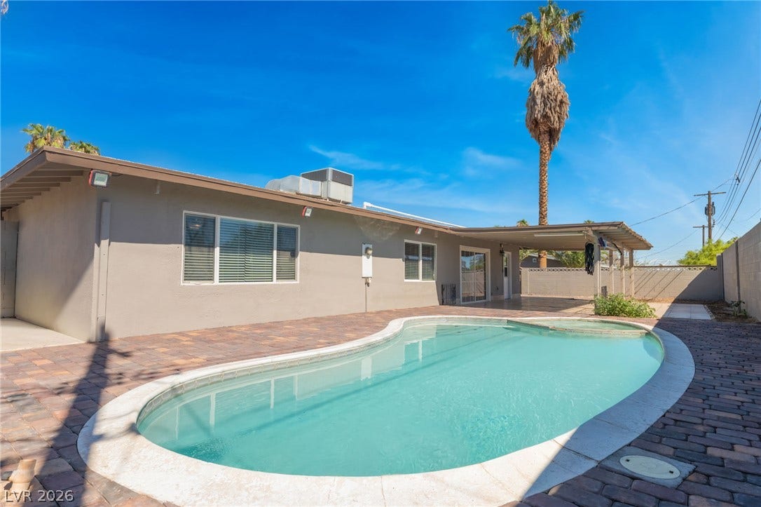 A sparkling in-ground pool anchors the backyard space lined with modern paver block decking.