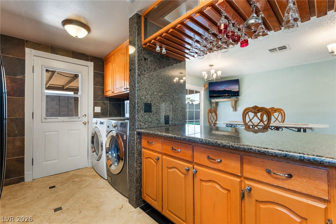 Gleaming stone countertops and a convenient laundry setup enrich this versatile utility area.