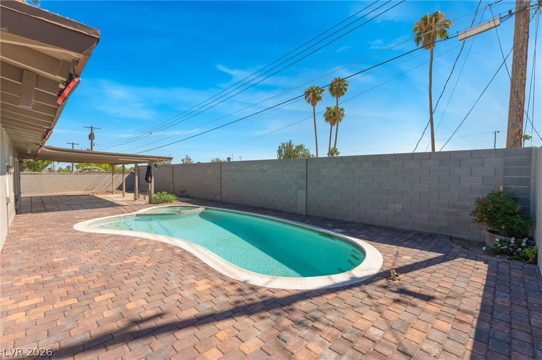 An inviting backyard swimming pool is bordered by clean paver decking and high privacy walls.