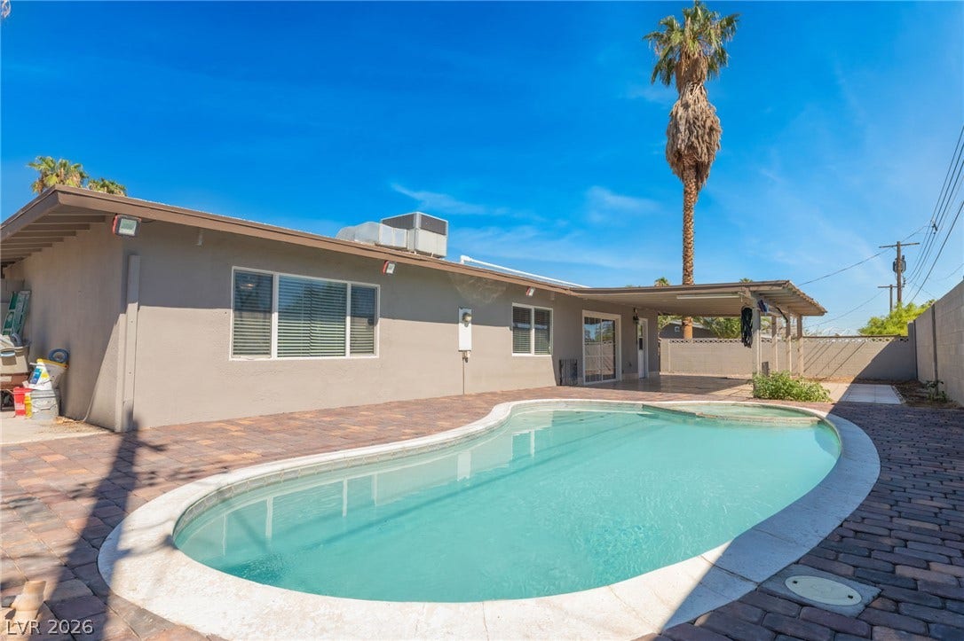 An inviting backyard oasis showcases a sparkling swimming pool surrounded by a spacious paver patio.