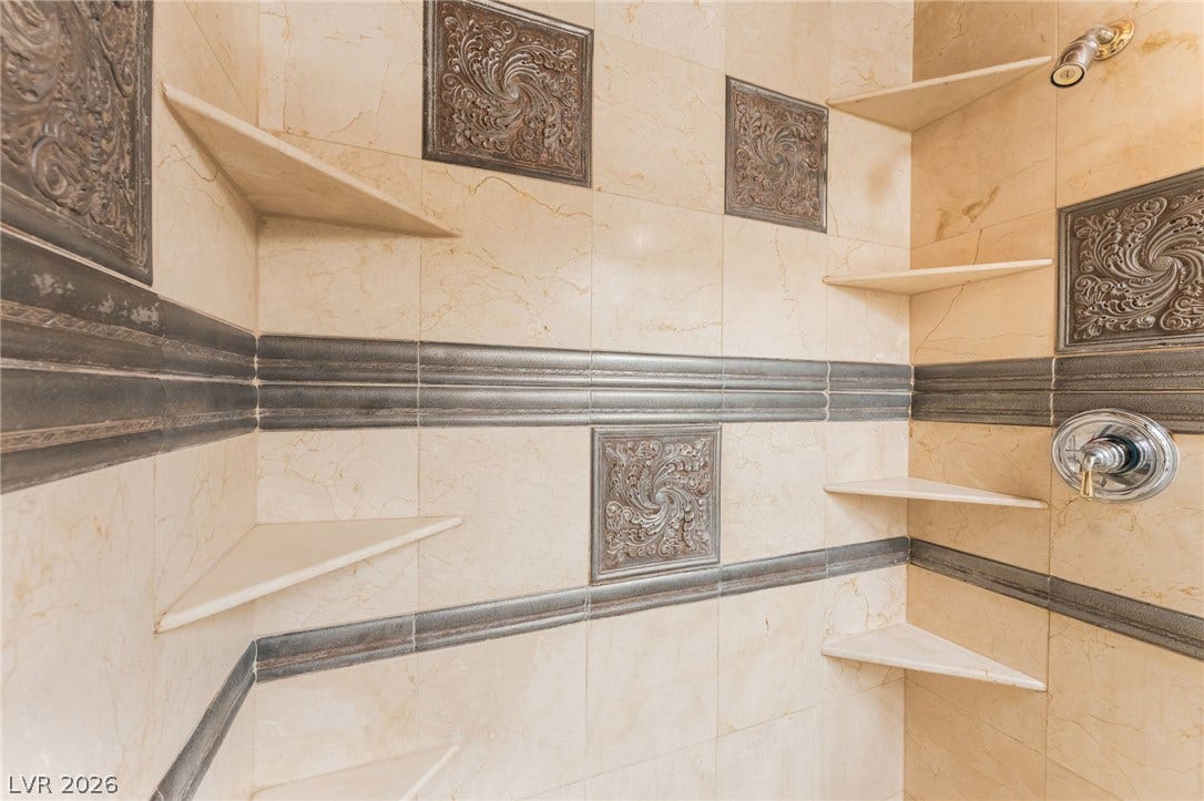 Ornate tilework and built-in shelving define this custom walk-in shower enclosure.