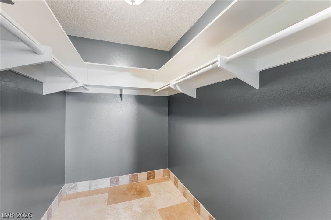 Ample built-in shelving and tile flooring maximize storage in this functional walk-in closet.