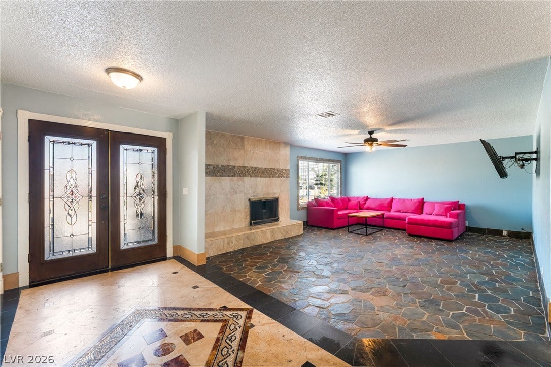 A spacious formal entryway flows directly into a large living area with textured stone flooring.