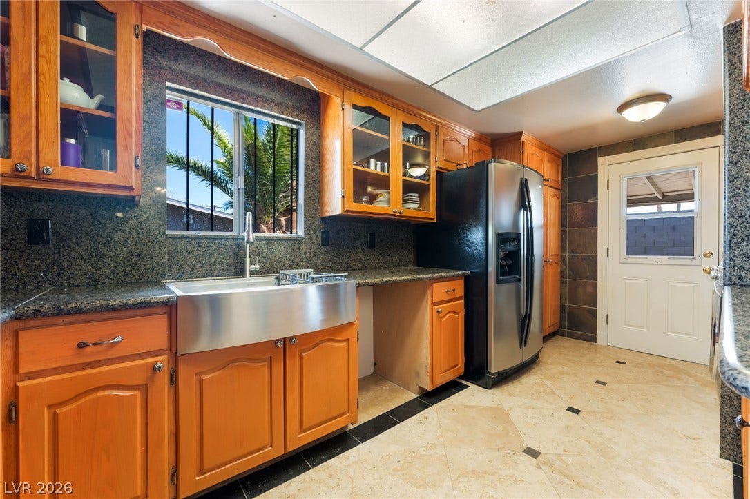 Rich wood cabinetry and stone countertops accent this kitchen featuring a stainless steel apron sink.