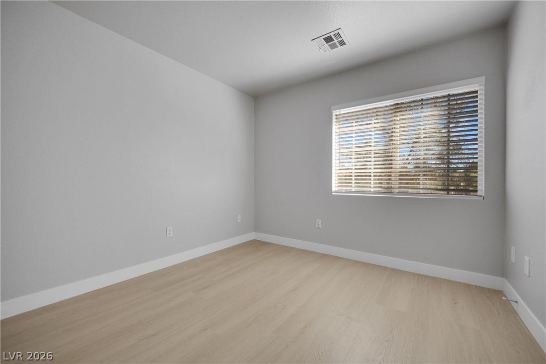 Smooth wood floors and tall baseboards define this versatile, naturally lit secondary bedroom.