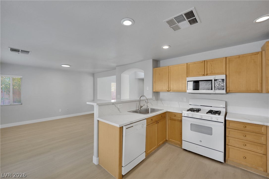 Natural wood cabinetry and stone countertops accent this light-filled culinary space with open floorplan connectivity.