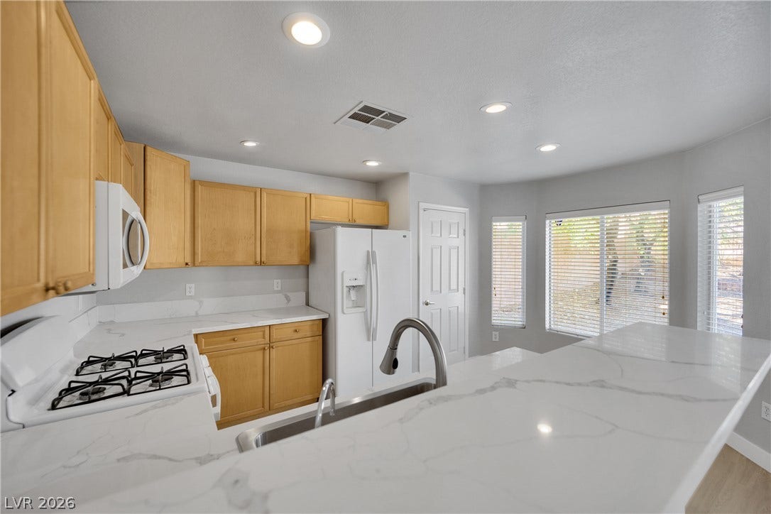 Veined stone countertops and wood cabinetry elevate this bright cooking space.