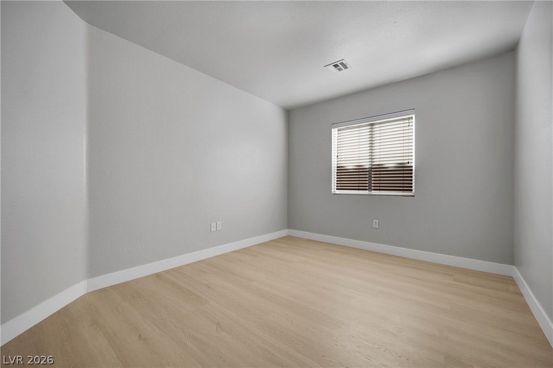 Smooth wood-look flooring and a bright window define this versatile bedroom space.