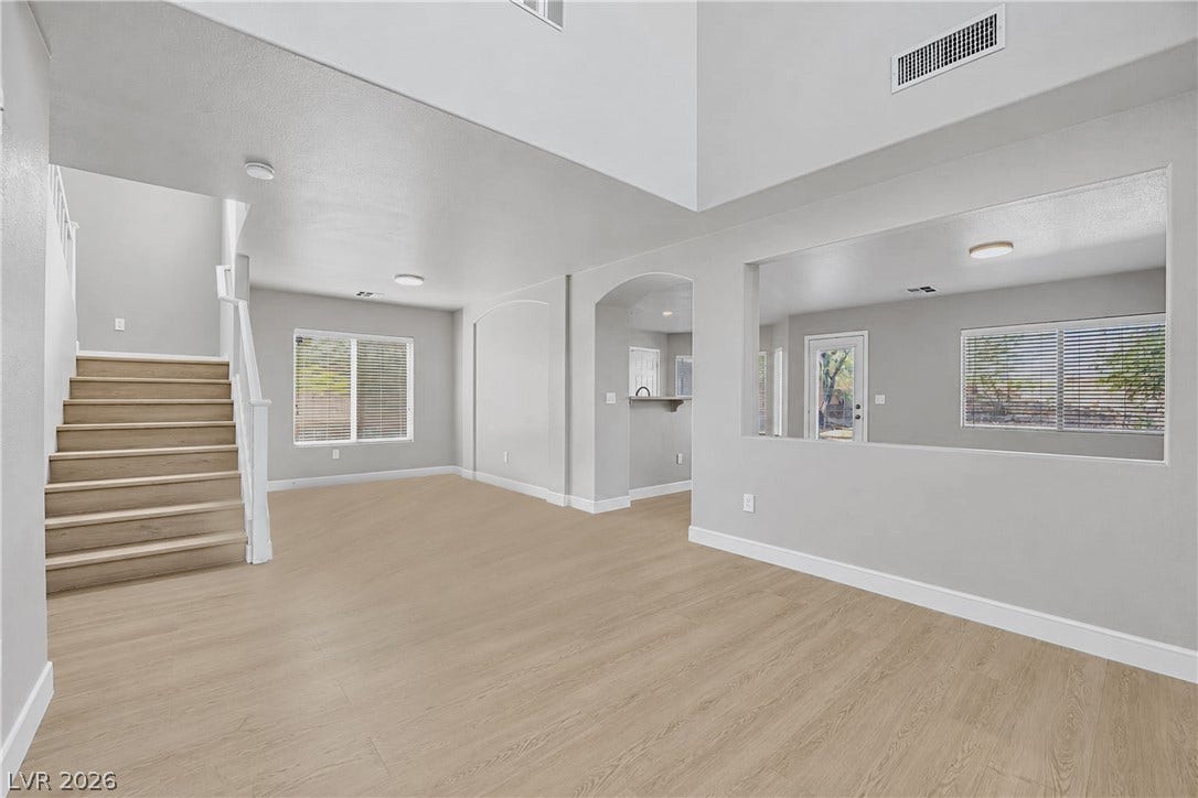 Hardwood floors and soaring high ceilings define this light-filled, open-concept main living space.