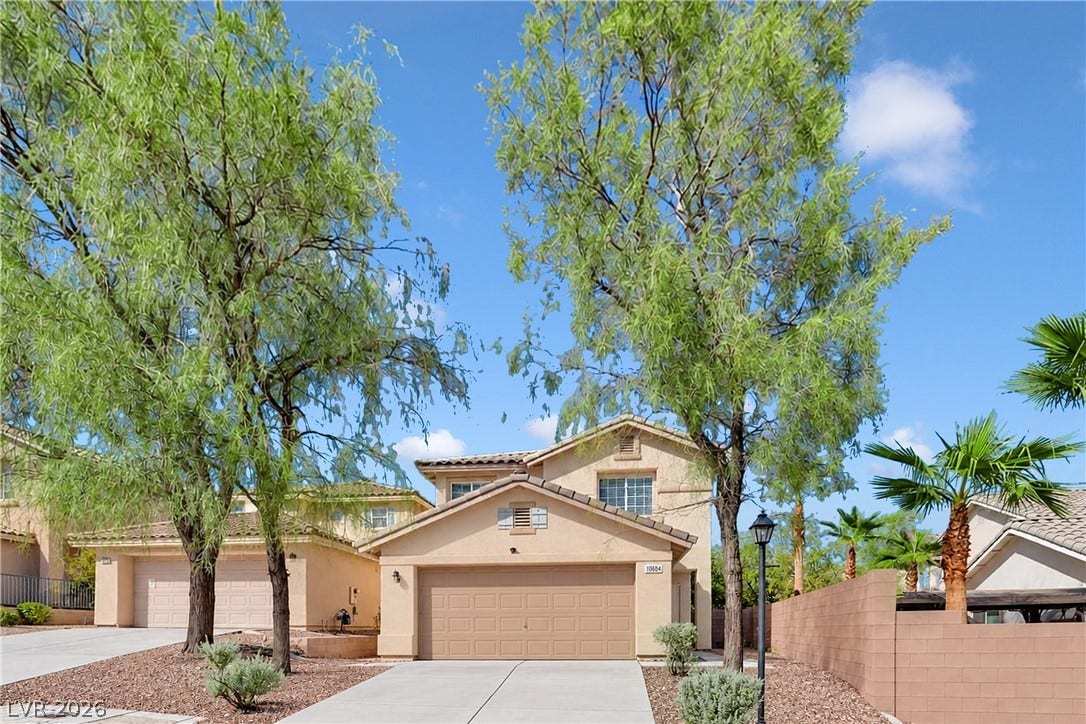 Mature trees frame a classic suburban exterior with stucco finishes and a tile roof.