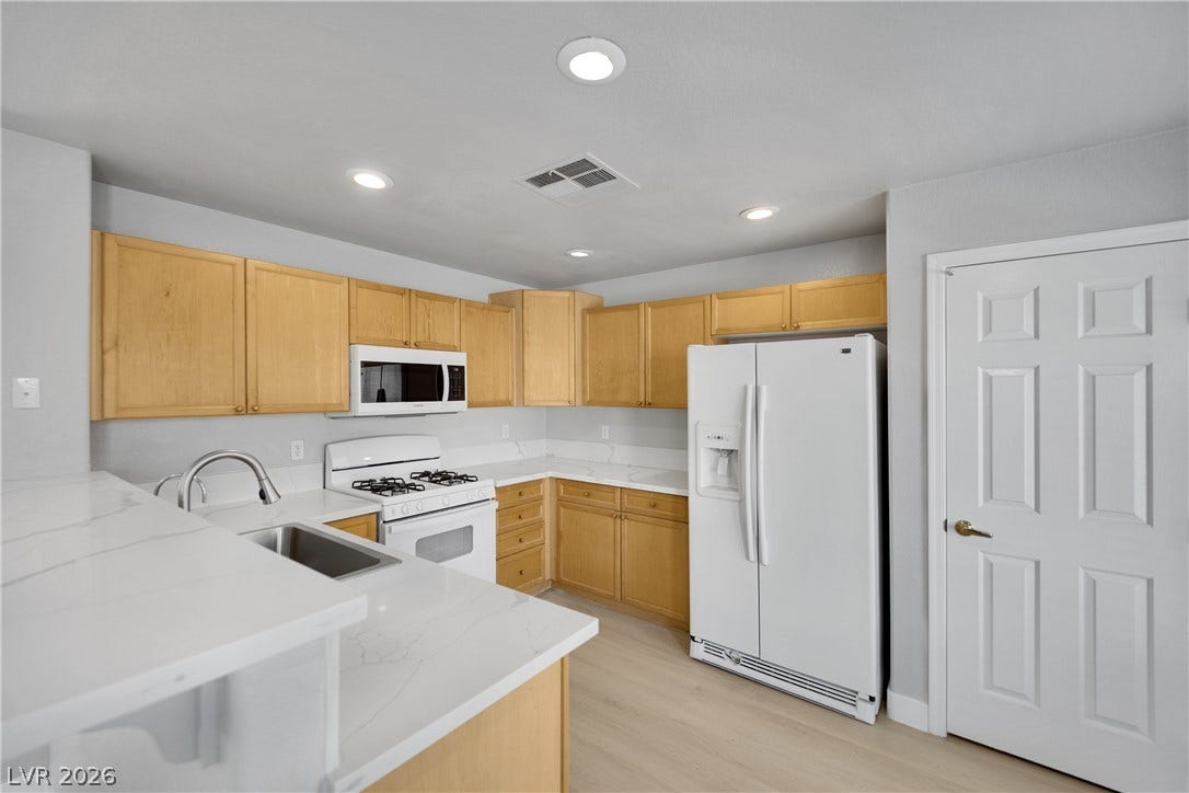 Warm wood cabinetry pairs with stone countertops in this functional, well-lit kitchen layout.