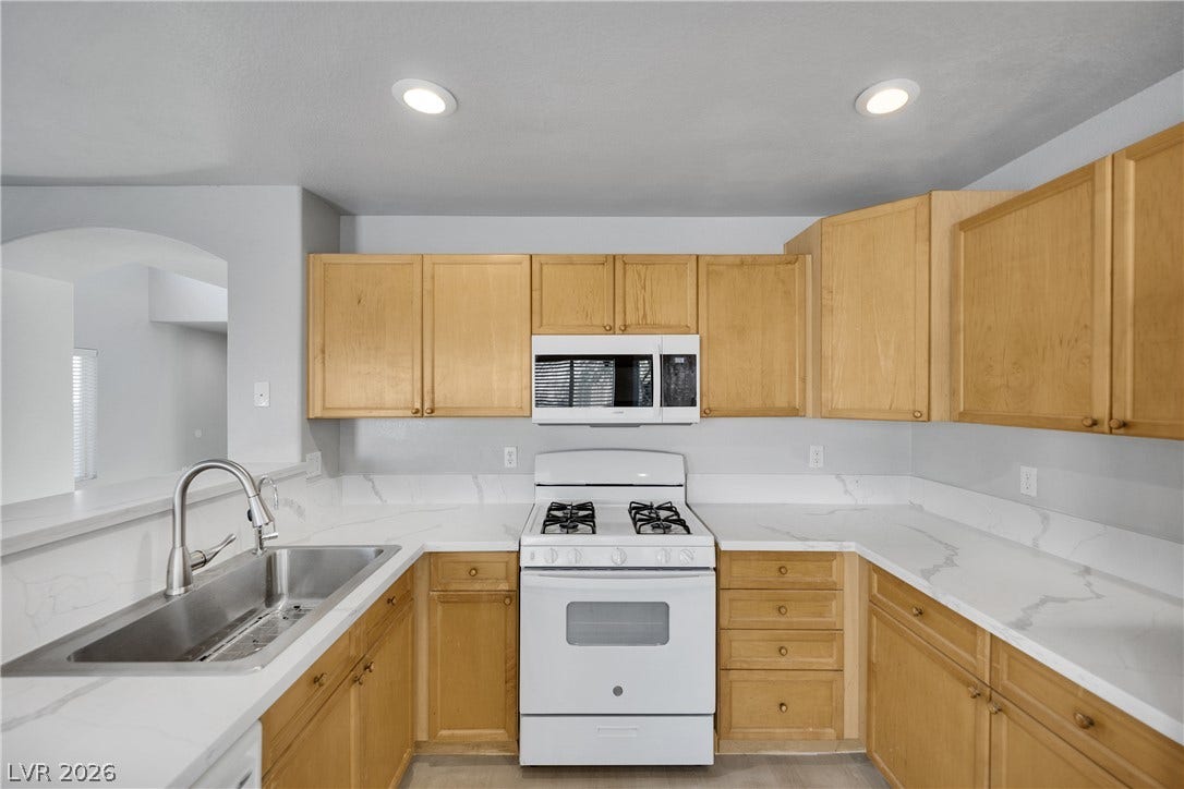 Natural wood cabinetry pairs beautifully with stone counters in this functional cooking space.