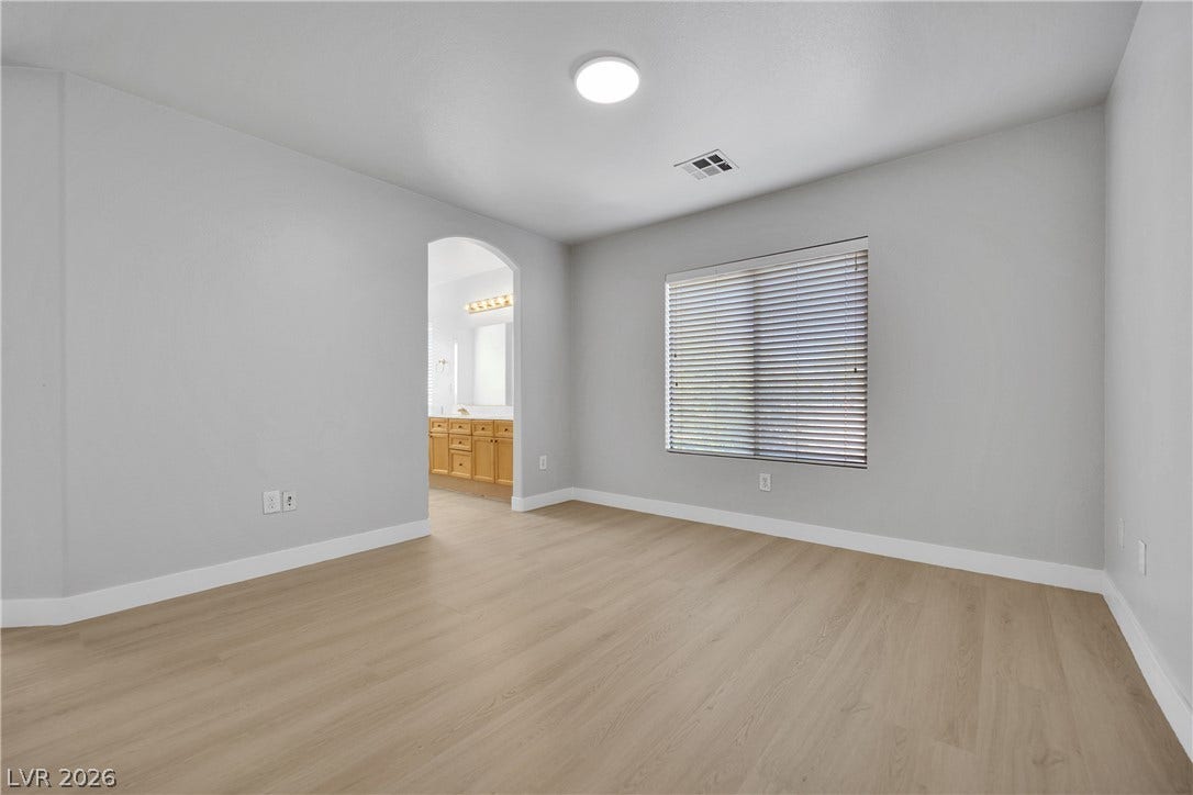 Smooth wood-look flooring and an arched doorway define this serene primary suite.