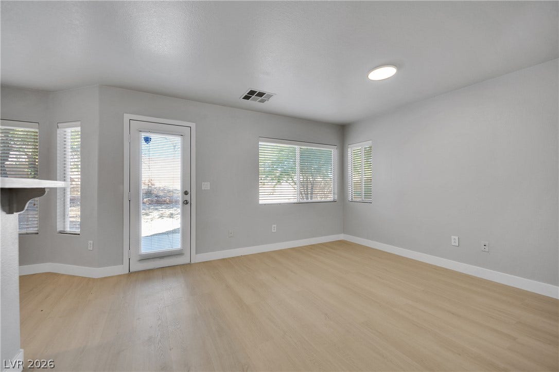 Smooth wood-style flooring and multiple windows create an inviting, open atmosphere in this living area.