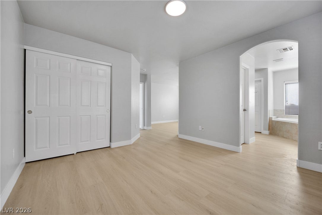 Smooth wood flooring and a wide arched doorway create an inviting, open transition between rooms.